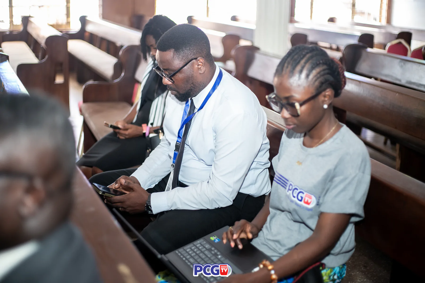 PCGTV media team members working with a laptop and mobile devices