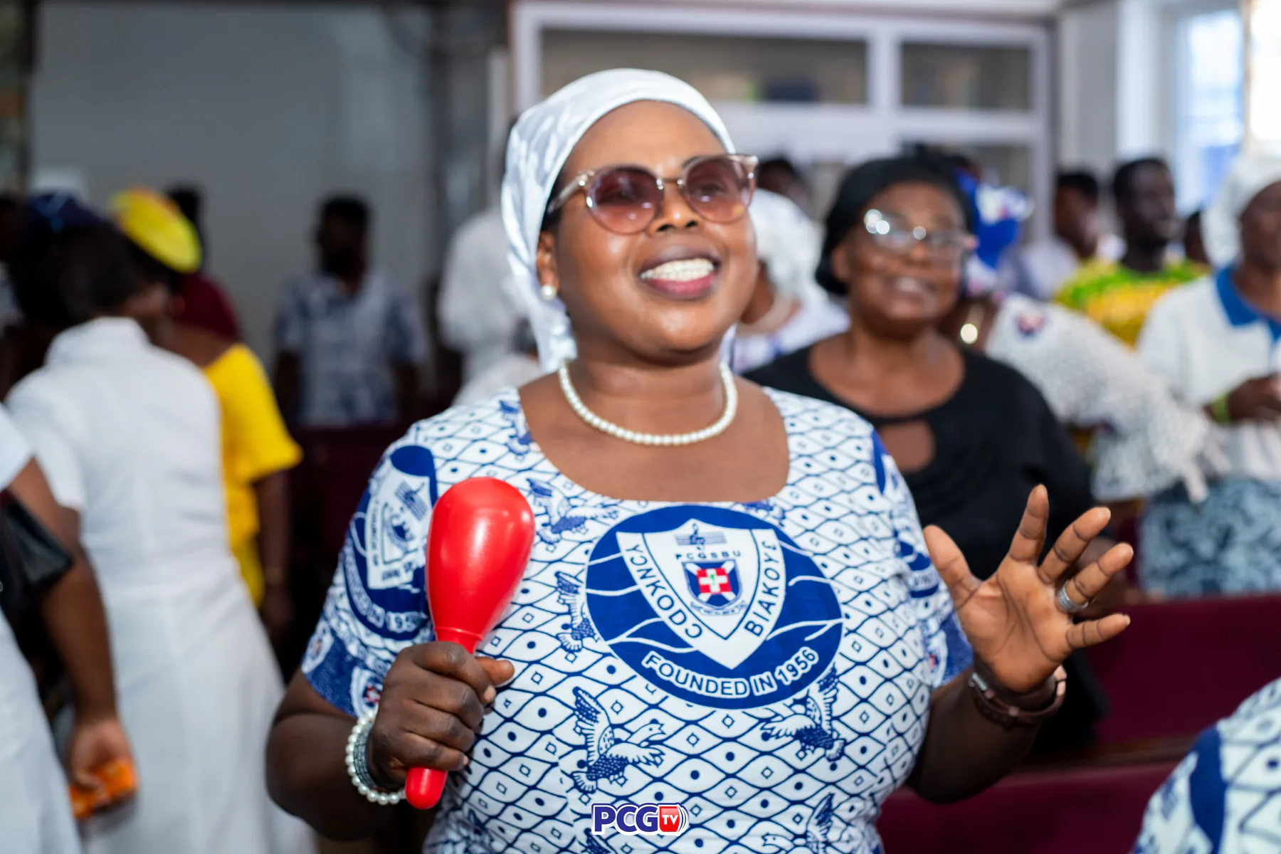 A Presbyterian woman singing and holding a red shaker