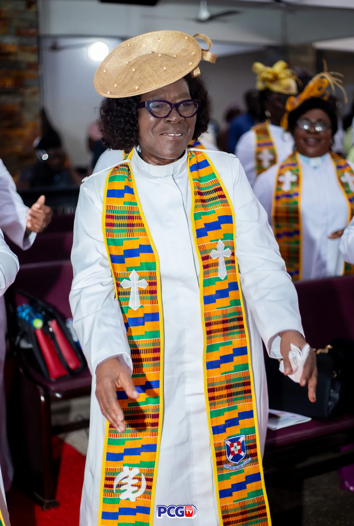 A female Presbyterian minister in white and kente standing in church