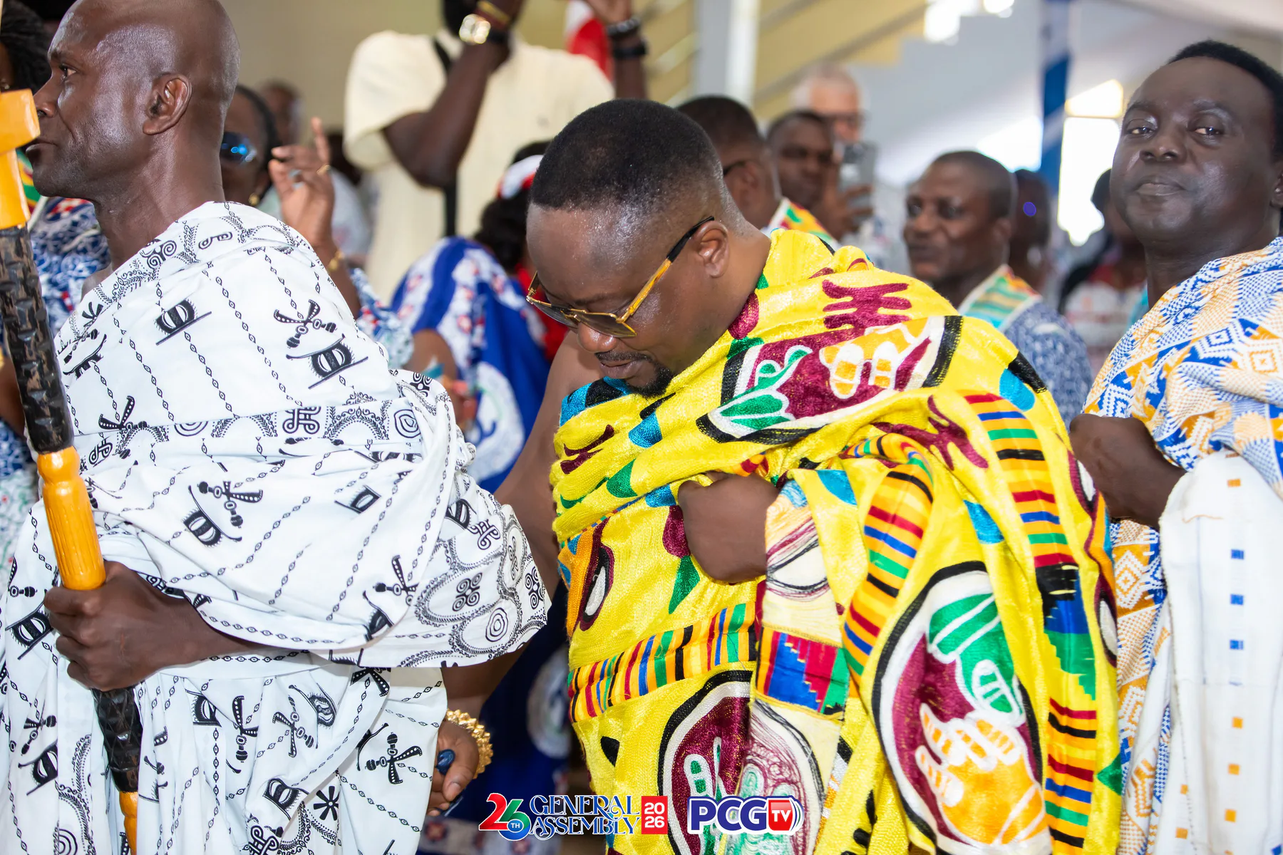 Men wearing colourful Ghanaian cloth during an assembly