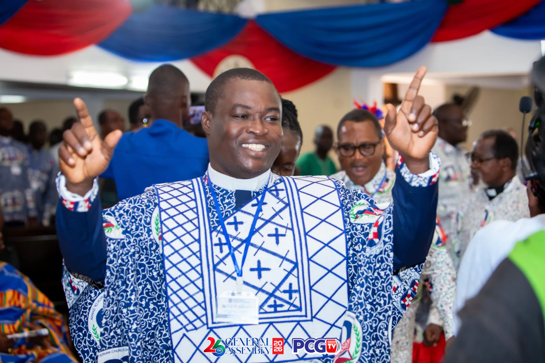 A Presbyterian minister smiling and raising both hands during worship